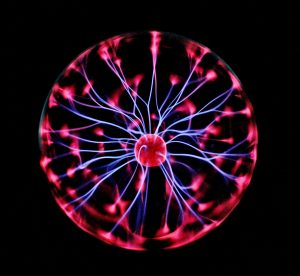 Close-up of a plasma globe with vibrant neon sparks against a dark background is how you can think of PEMF or pulsed electromagnetic field.